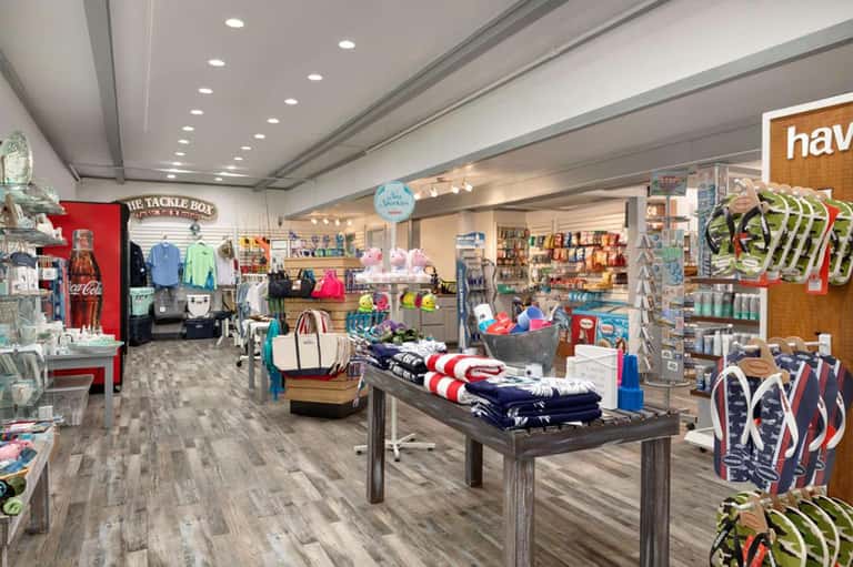 Retail shop interior displaying clothing, accessories, and merchandise with wooden display tables