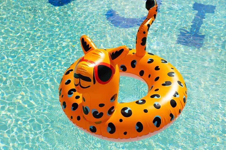 Orange leopard-spotted inflatable float ring in bright blue pool water
