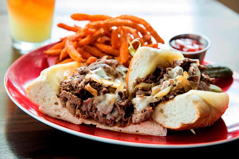 Pulled pork sandwiches with sweet potato fries and beverages on a red plate