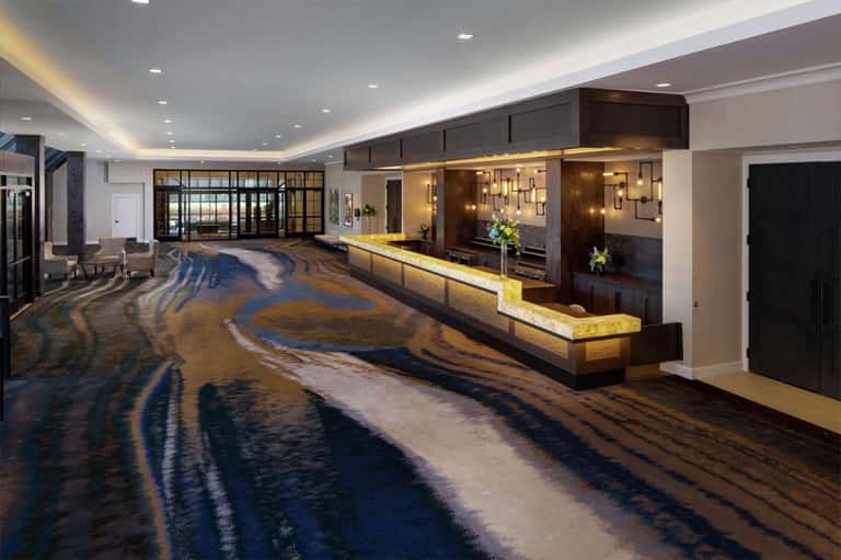 Hotel lobby with polished floors and illuminated reception desk against brown brick wall