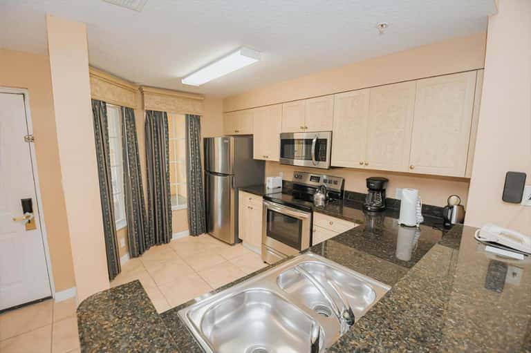 Hotel kitchen with stainless steel appliances, granite counters, and light wood cabinets