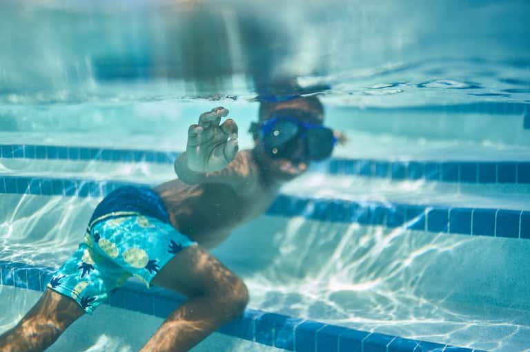 Underwater view of a swimmer doing freestyle stroke in a clear blue pool