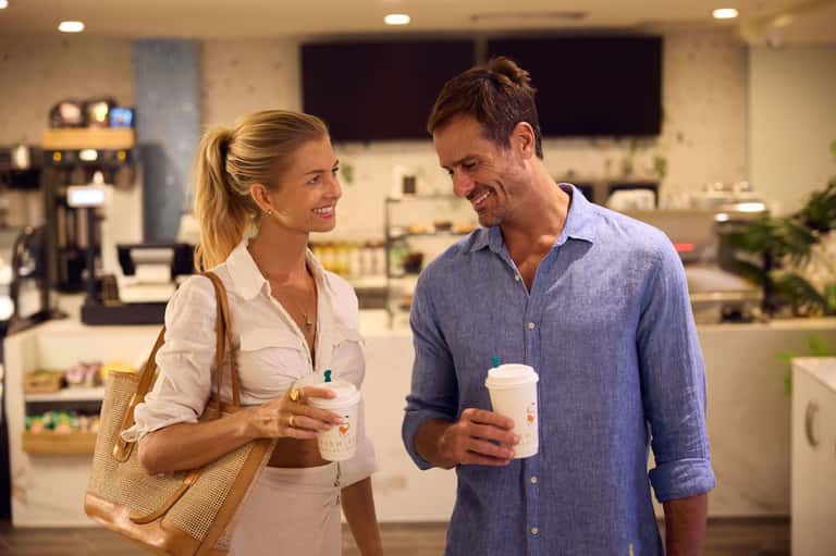 Man and woman chatting in modern hotel lobby holding coffee cups