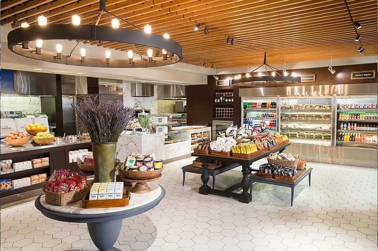 Modern hotel convenience store with bright lighting, fresh produce, refrigerated beverages, and snack displays