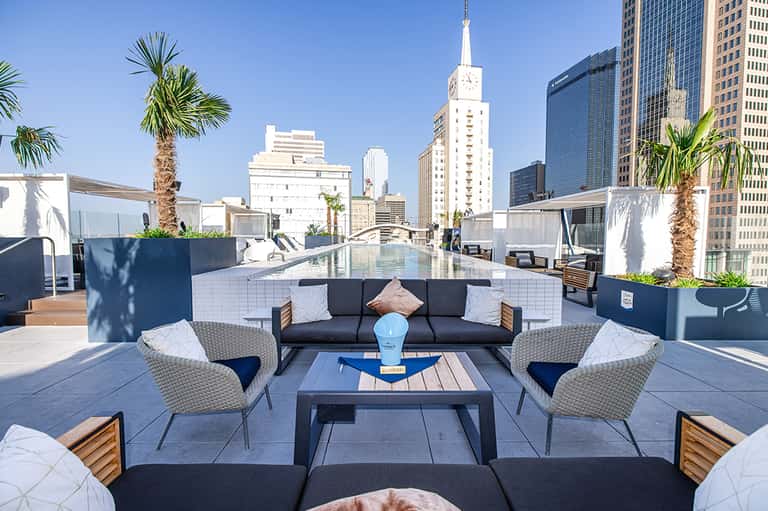 Modern rooftop lounge with city skyline views, palm trees, and contemporary seating
