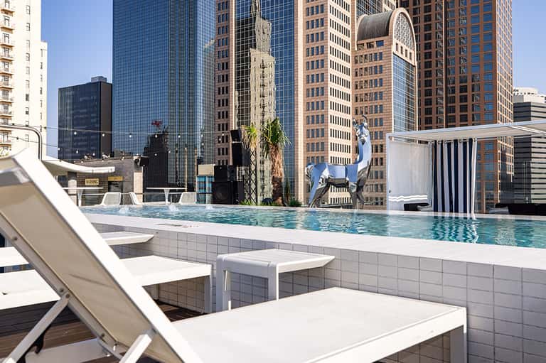 Rooftop infinity pool with downtown skyline views and lounge chairs