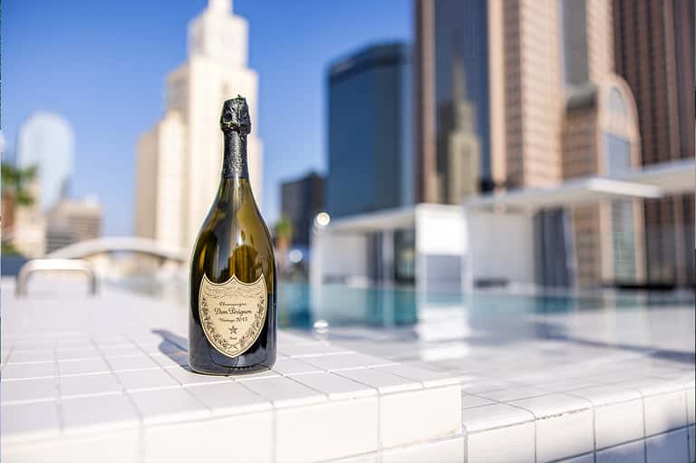 Dom Pérignon champagne bottle on rooftop terrace overlooking downtown city skyline and pool