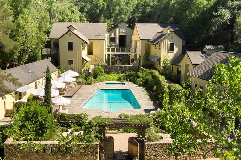 Aerial view of resort compound with yellow cottage-style buildings and central swimming pool
