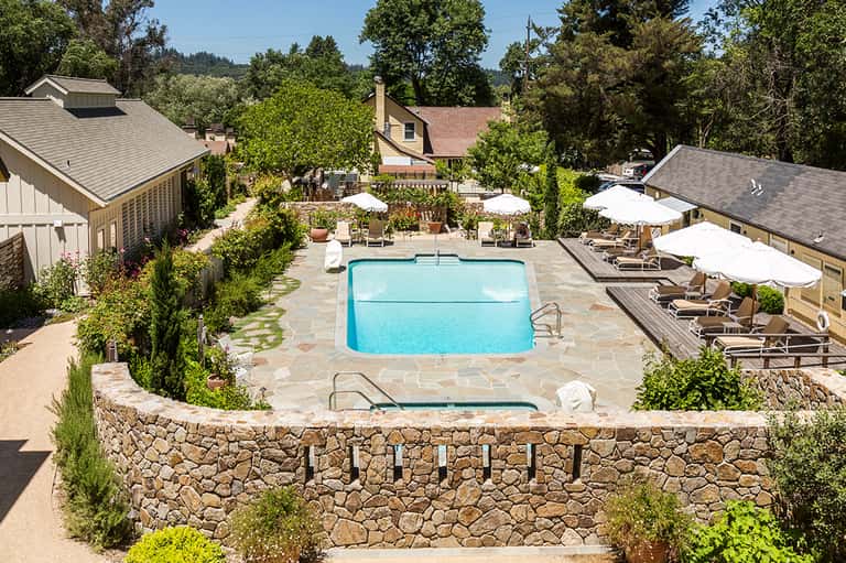 Resort pool surrounded by stone walls, lounge chairs, and umbrella seating areas