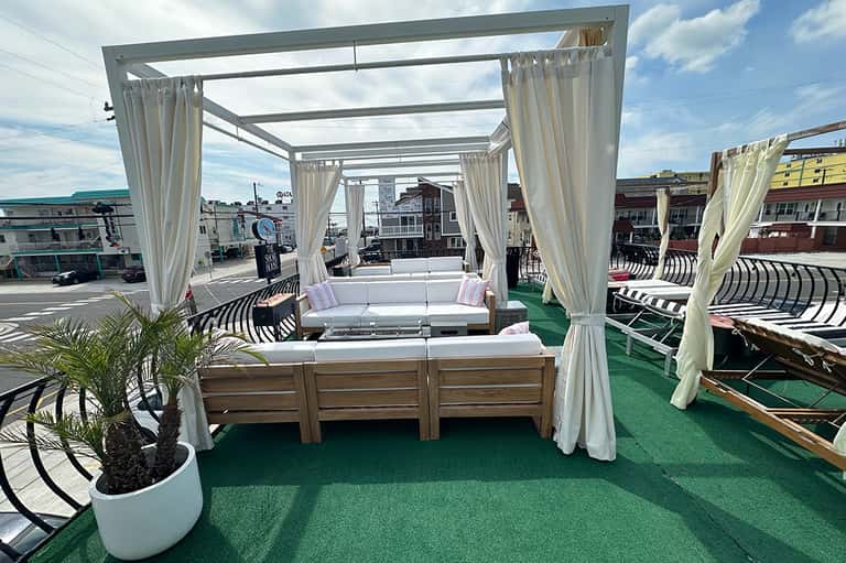 Rooftop deck with white canopy lounge structures on artificial green turf overlooking a coastal town