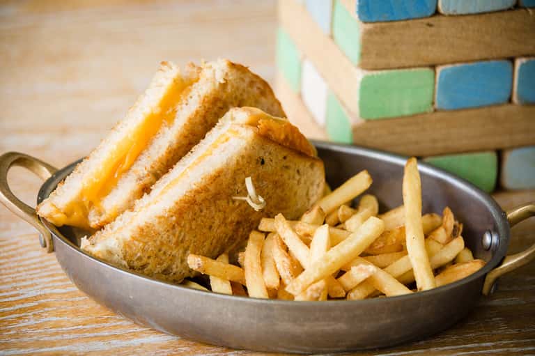 Grilled cheese sandwich with melted cheddar and french fries served in a cast iron skillet
