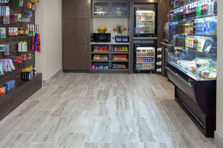 Hotel convenience store with refrigerated cases, shelving units stocked with beverages and snacks