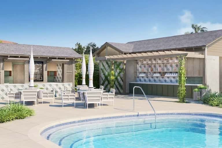 Resort pool area with white lounge chairs, pergola shade structures, and modern poolside amenities