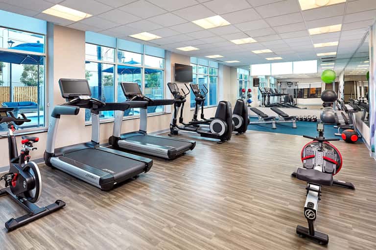 State-of-the-art fitness center with treadmills, exercise bikes, and equipment overlooking outdoor pool