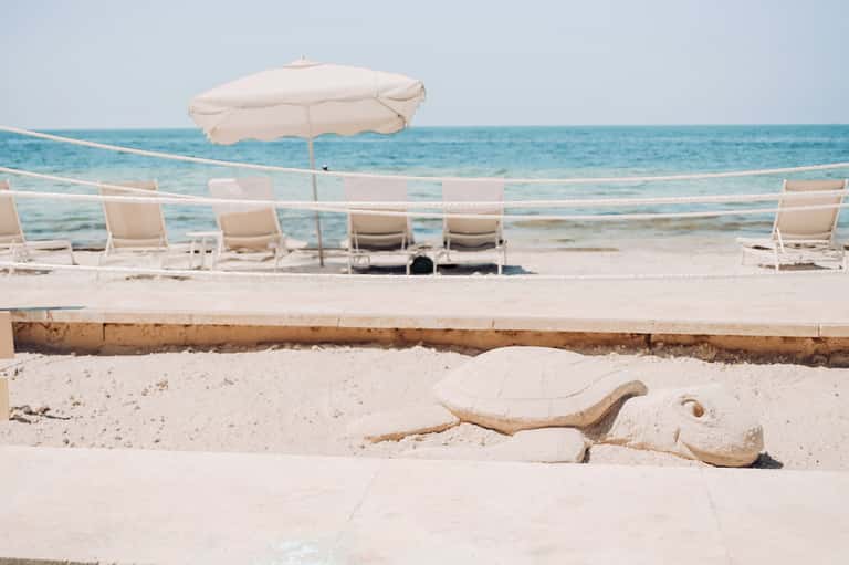 Beach lounge area with white umbrellas, chairs, and turquoise ocean view