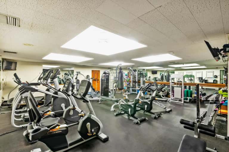 Bright fitness facility with stationary bikes, ellipticals, and strength training equipment