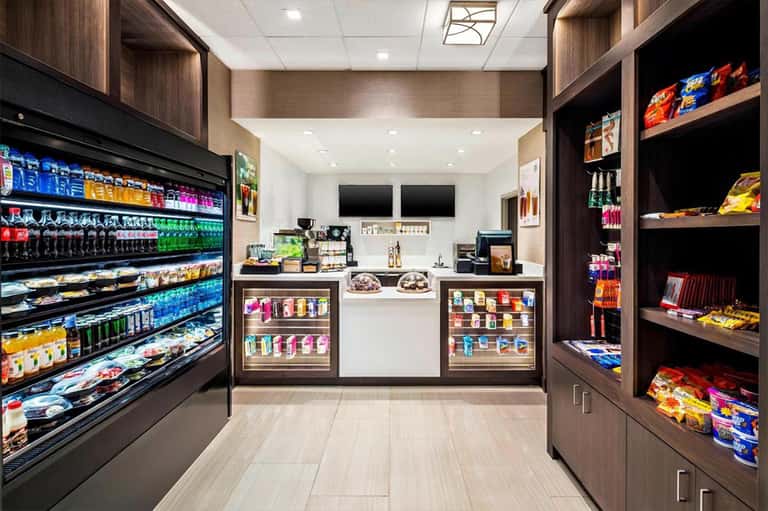 Modern convenience store interior with refrigerated cases, shelving, and checkout counter