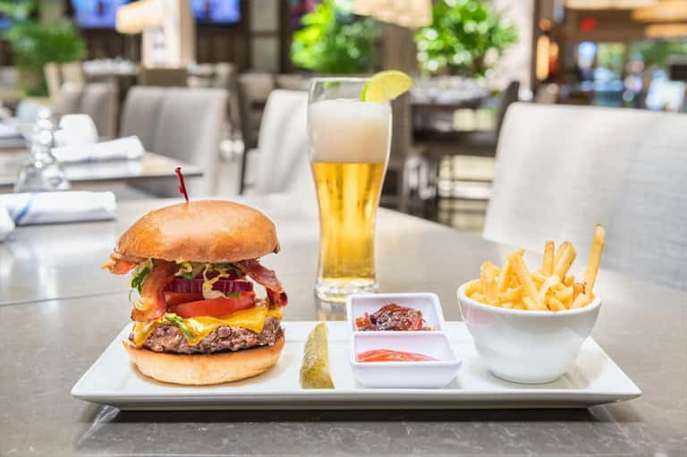 Gourmet burger with bacon and cheese, fries, and beer in hotel restaurant