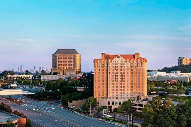 Two high-rise resort towers at dusk with illuminated facades and cityscape in background