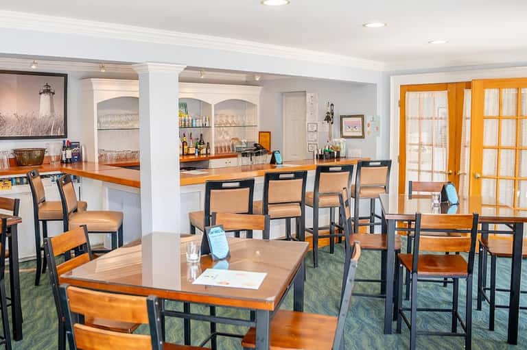 Casual dining area with wooden tables, bar counter, and orange accents
