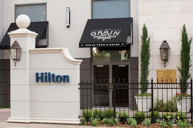 Hilton hotel entrance with black awning for Grain restaurant and white stone facade