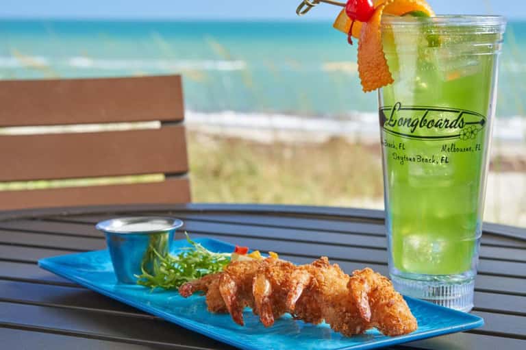 Fried shrimp platter with green cocktail and ocean view from beachfront dining table
