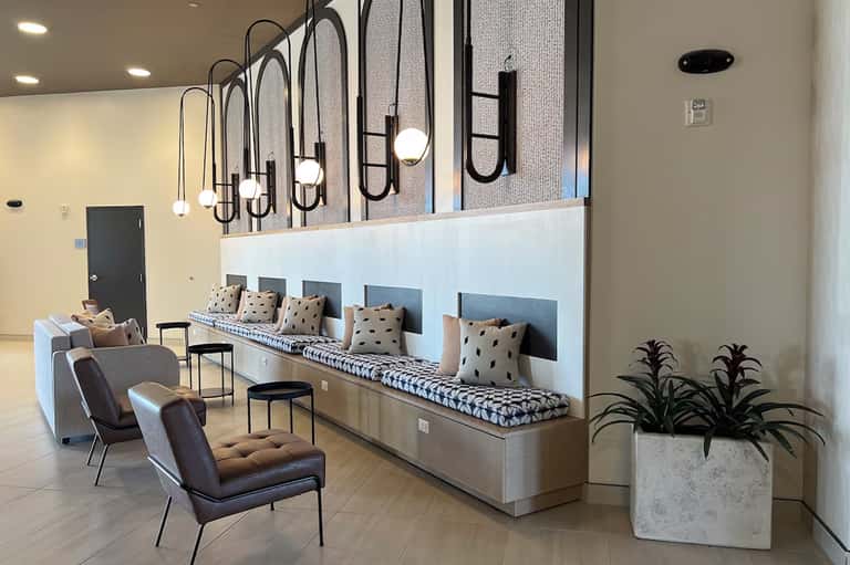 Modern hotel lobby lounge with bench seating, pendant lights, and contemporary furnishings