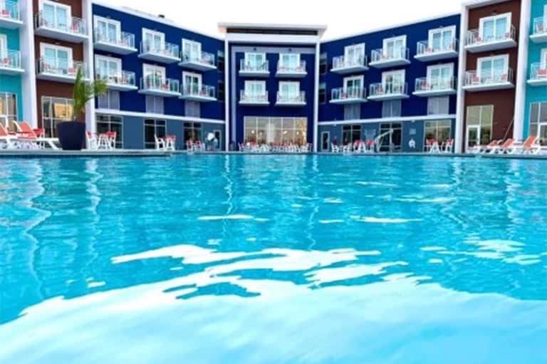 Modern resort courtyard pool with blue water, colorful apartment balconies, and lounge chairs