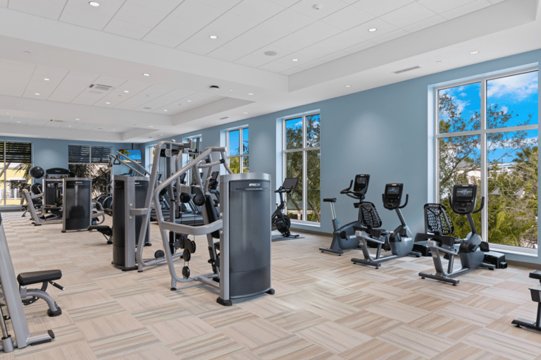 Bright fitness center with exercise equipment, wooden flooring, and large windows overlooking landscape