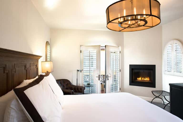 Luxurious hotel bedroom with fireplace, white bedding, and balcony doors