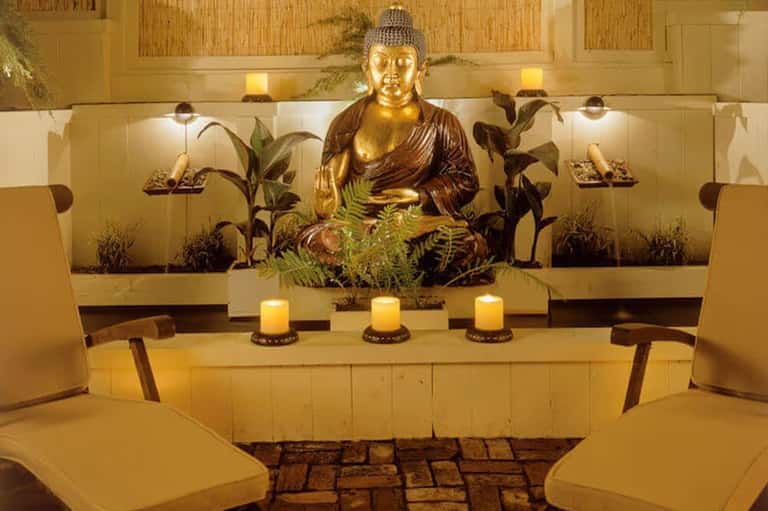 Serene spa relaxation room with golden Buddha statue and candlelit ambiance