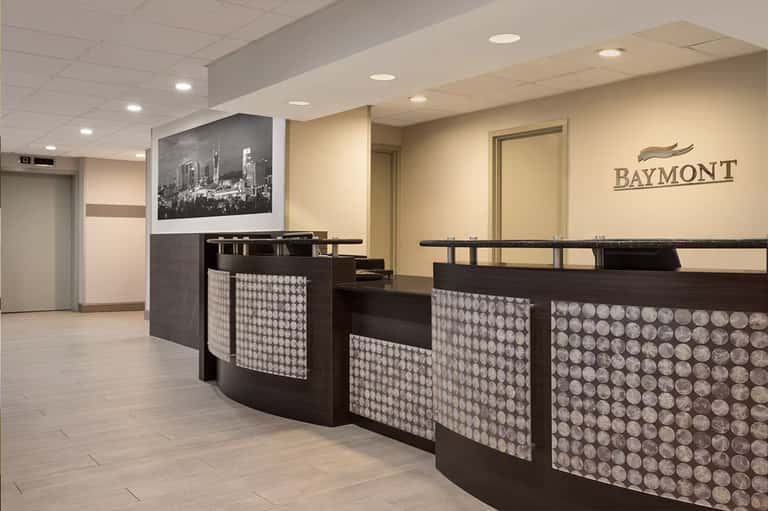 Hotel reception desk with geometric patterned panels and Baymont branding in neutral tones