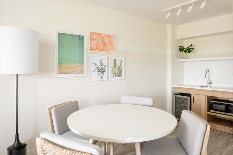 Modern dining area with white round table, gray chairs, and framed botanical artwork on walls