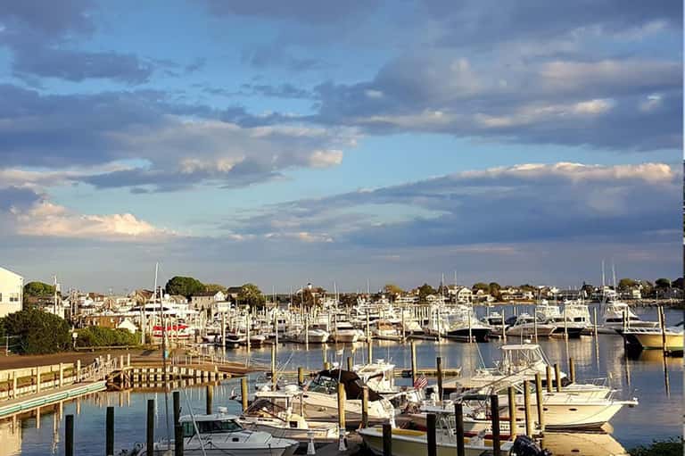 Marina at dusk with sailboats docked at wooden piers under a cloudy blue sky