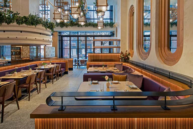 Modern restaurant interior with curved wooden details, purple booths, and contemporary oval wall art