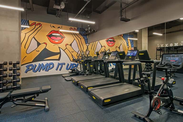 Fitness center with treadmills, exercise bikes, dumbbells, and motivational pop art wall mural