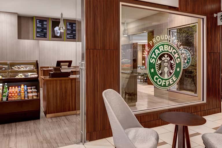 Modern Starbucks coffee shop interior with wood paneling, display cases, and seating area