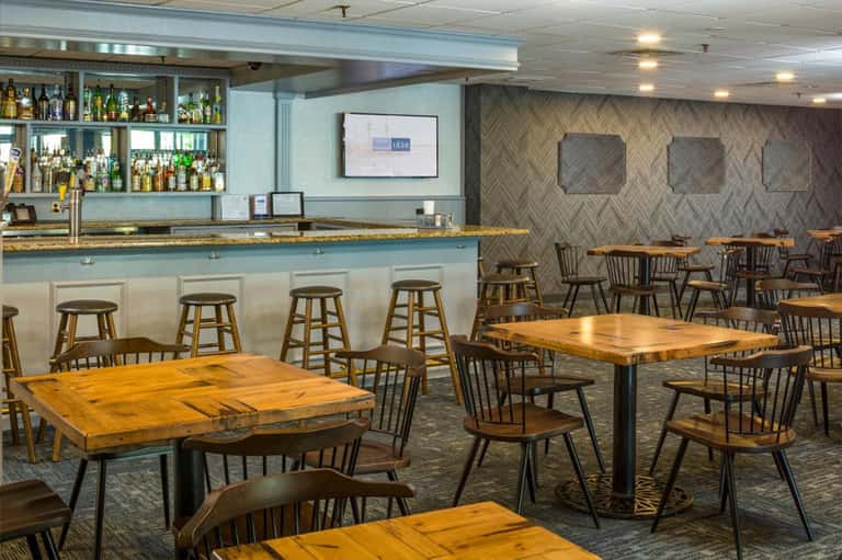 Casual dining area with wooden tables, bar seating, and herringbone patterned accent wall