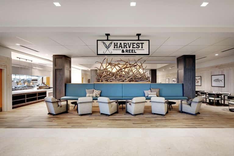 Harvest & Reel restaurant lobby with blue seating, wooden accent wall, and driftwood sculpture