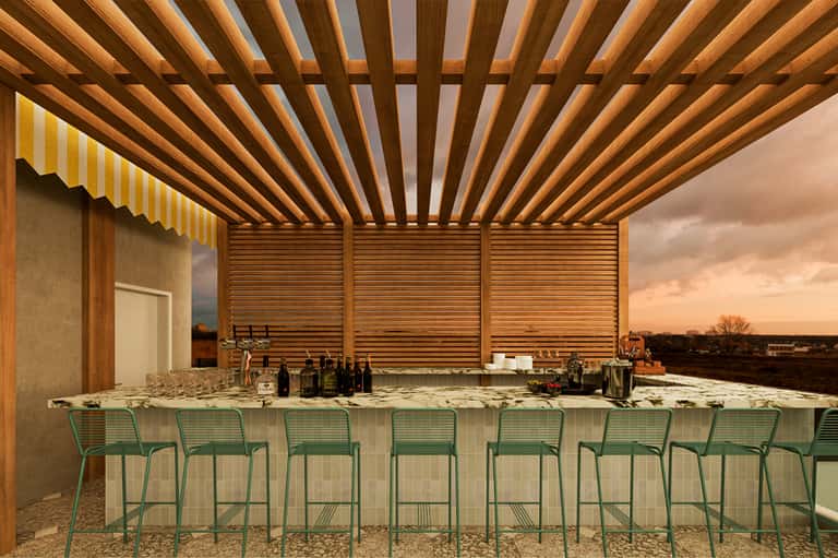 Modern wooden pergola bar structure with green metal bar stools overlooking a scenic horizon at sunset