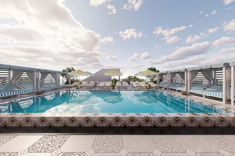 Resort pool with cabanas and lounge chairs under blue sky with fluffy clouds