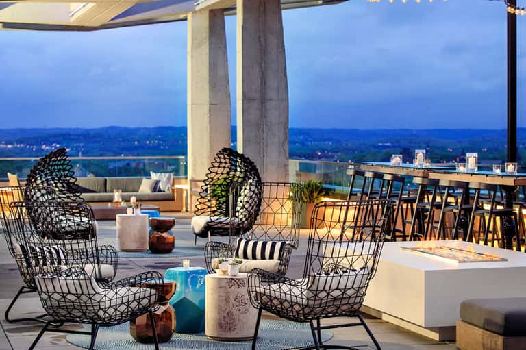 Modern rooftop lounge with black woven chairs overlooking valley and landscape at twilight