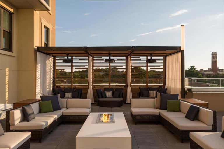 Luxury rooftop terrace with lounge seating, fire pit, pergola, and city skyline views