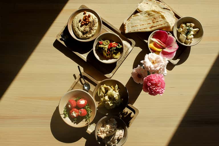 Overhead view of Mediterranean mezze platter with hummus, bread, vegetables, and flower garnishes