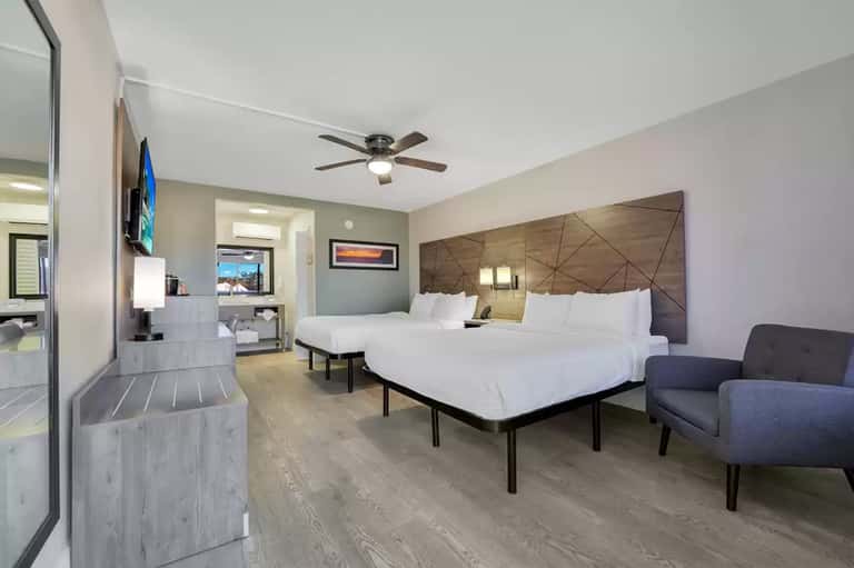 Modern hotel bedroom with two queen beds, geometric headboard, and contemporary furnishings
