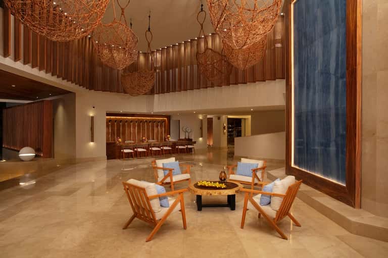 Luxury lobby with woven pendant lights, fireplace, wooden chairs, and modern furnishings on marble flooring