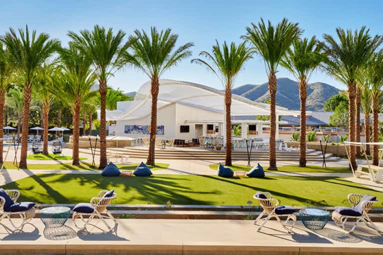 Palm-lined lawn with lounge chairs overlooking mountain views and contemporary white event pavilion