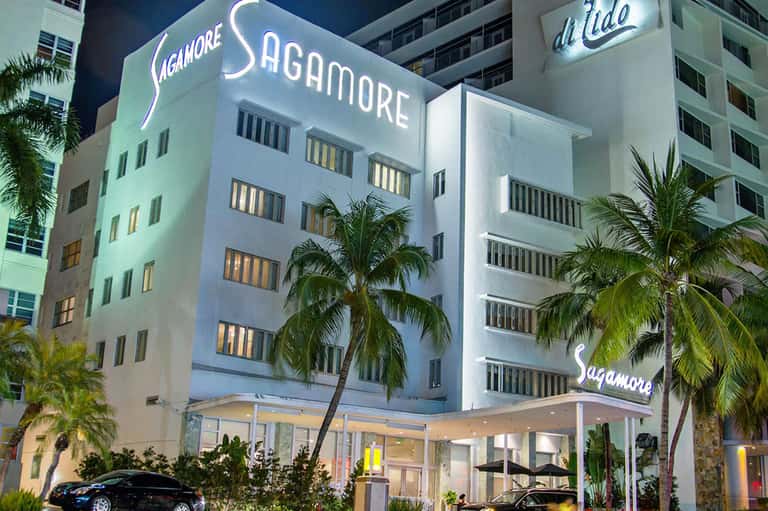 Sagamore Hotel exterior at night, white Art Deco building with illuminated signage and palm trees