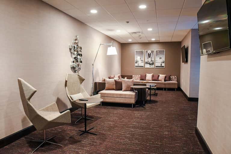 Contemporary hotel lounge with beige seating, brown accent wall, framed artwork, and flat-screen TV
