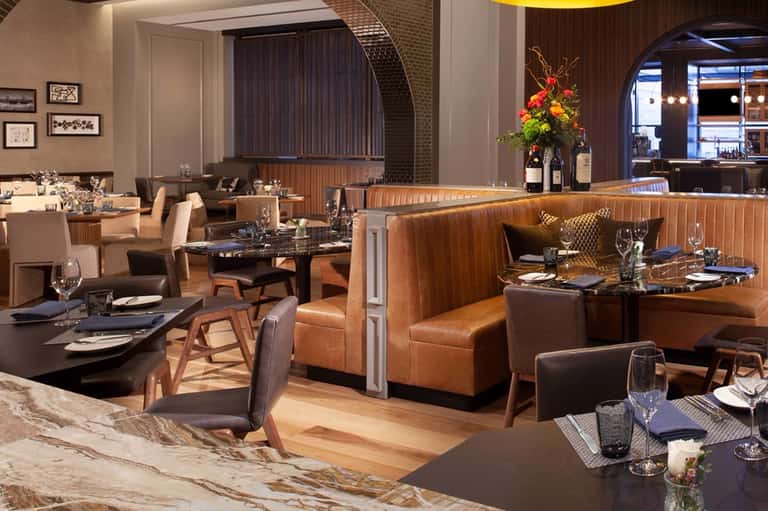 Fine dining restaurant with cognac leather booths, dark tables, and wood accents